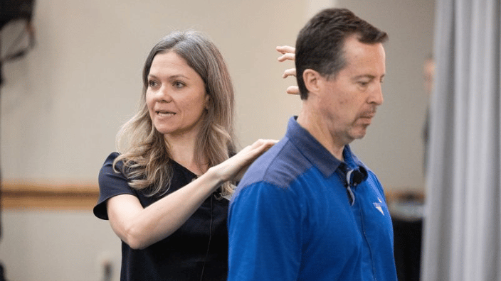 Woman demonstrating how to massage neck area on man