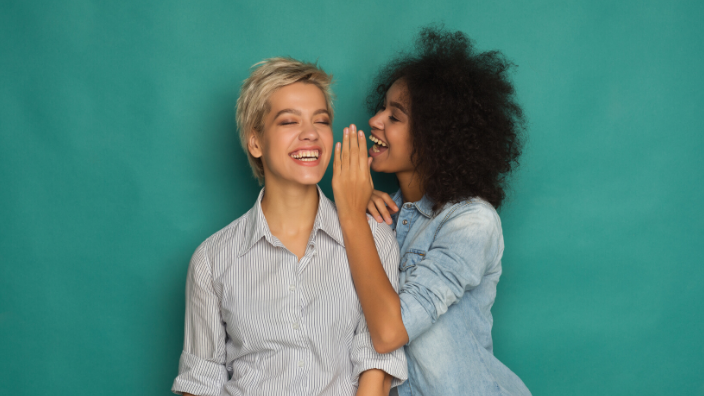 woman whispering a secret to another woman