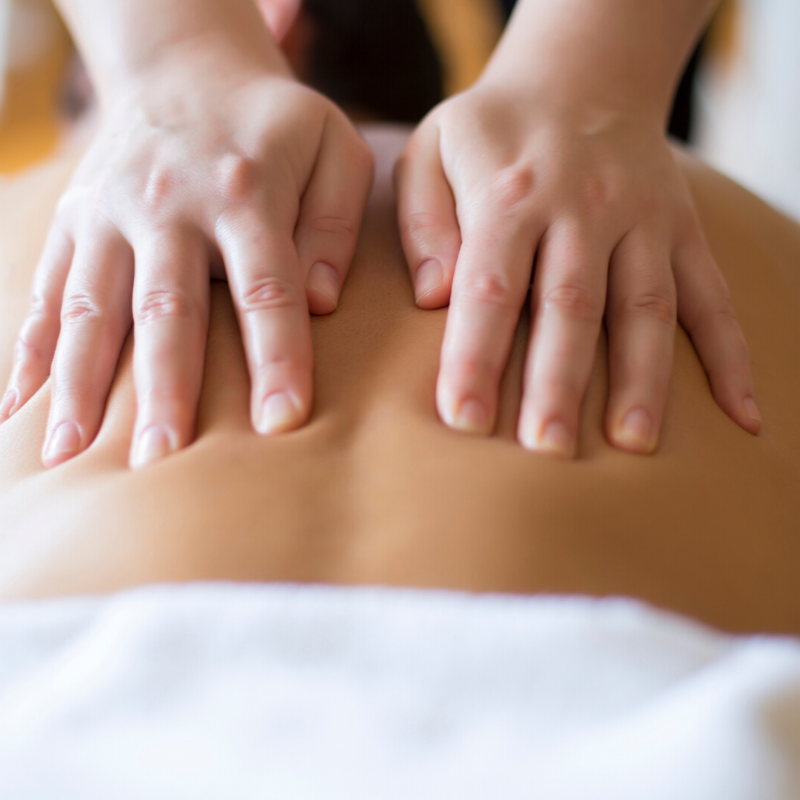 massage therapist's hands massaging client's back